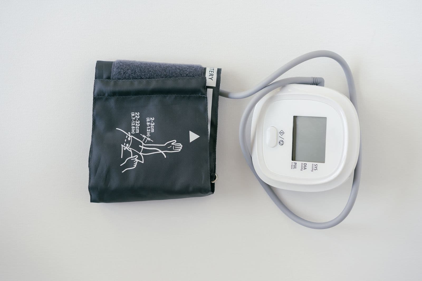 A digital blood pressure monitor and cuff on a plain background