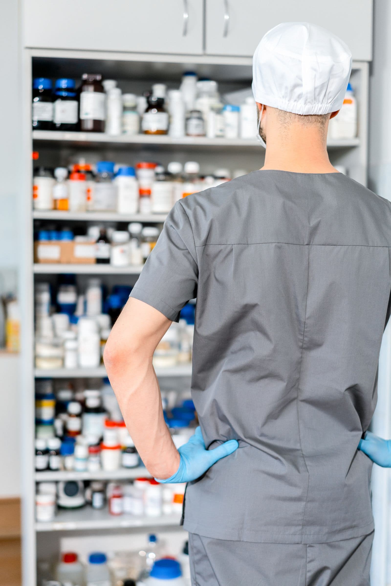 A pharmacist checking stocked medicine shelves in a dispensary
