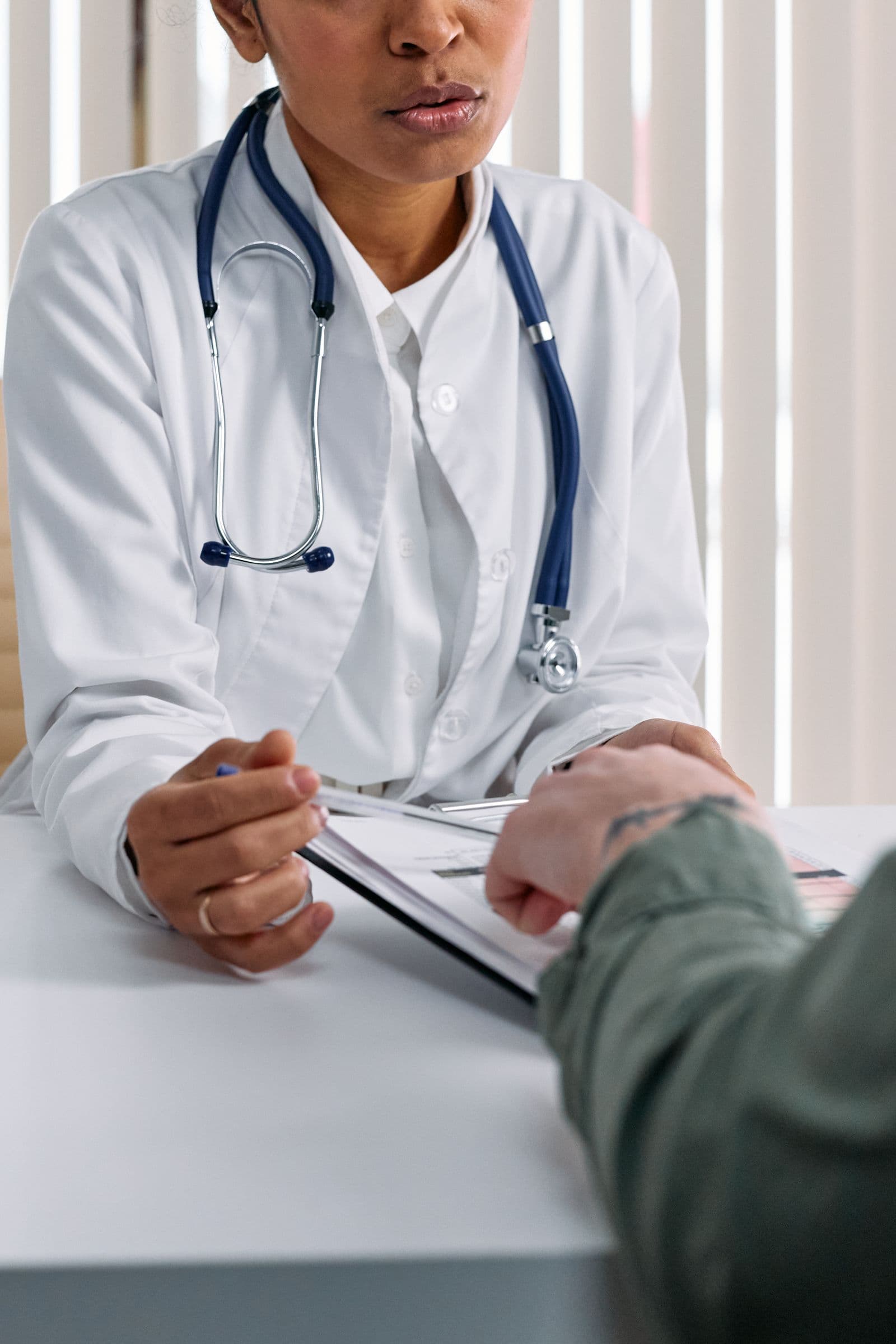 A doctor and patient reviewing medical notes together at a consultation desk
