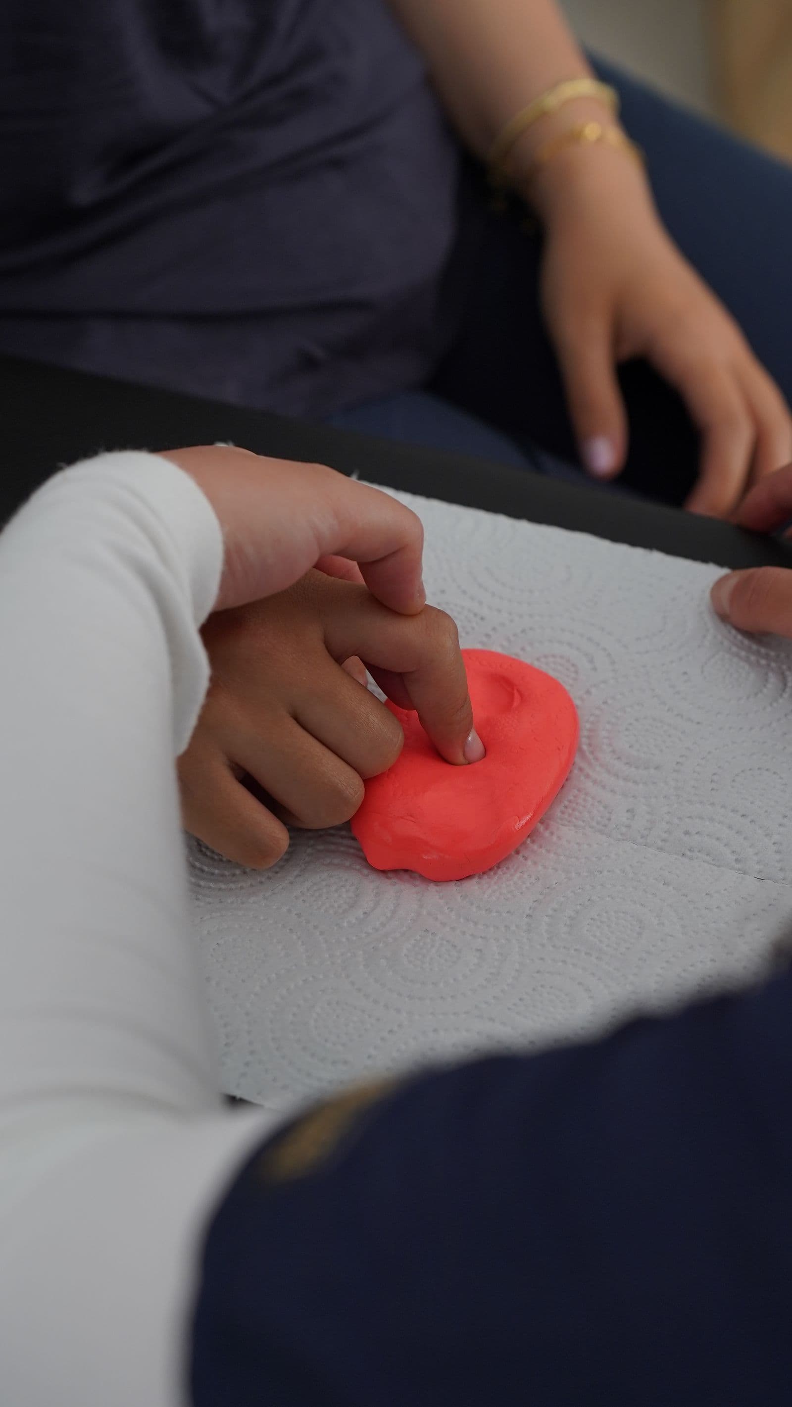 A child's hand pressing therapy putty during a hands-on session